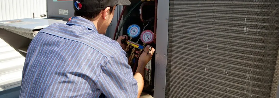 HVAC technician servicing a condenser unit in Newnan